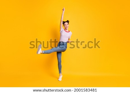 Photo of pretty shiny young girl dressed striped t-shirt pointing empty space dancing isolated yellow color background