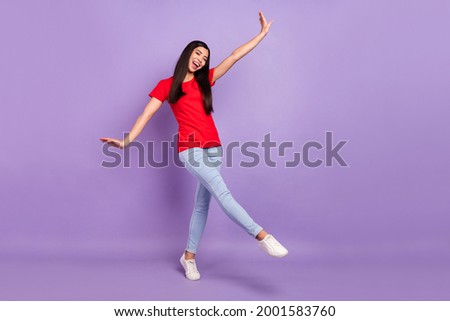 Photo of funny carefree woman dressed red t-shirt walking dancing smiling isolated purple color background
