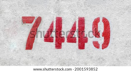 Red Number 7449 on the white wall. Spray paint. Number seven thousand four hundred and forty nine.