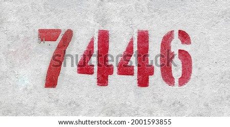 Red Number 7446 on the white wall. Spray paint. Number seven thousand four hundred and forty six.