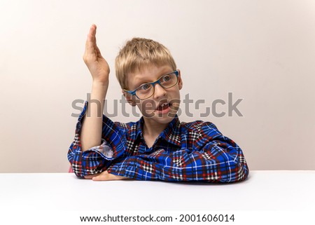 schoolboy with glasses raises his hand. boy in plaid shirt knows answer. Elementary school. Study online from home. Distance preparation for school in first grade. Quarantine at coronavirus school