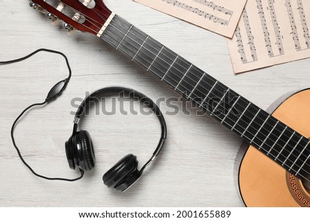 Composition with guitar and music notations on light wooden table, flat lay