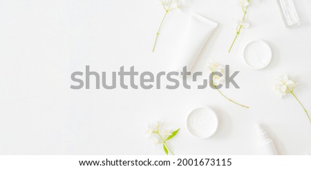 Flat lay composition with cosmetics and jasmine flowers on a light background