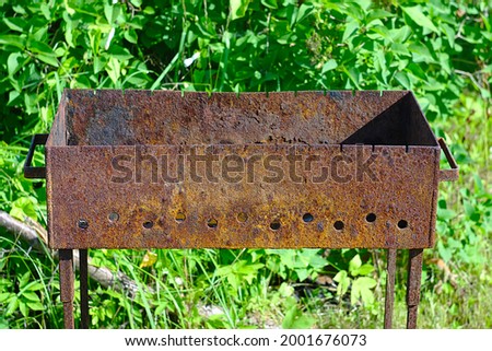 A rusty metal brazier on a green grassy lawn