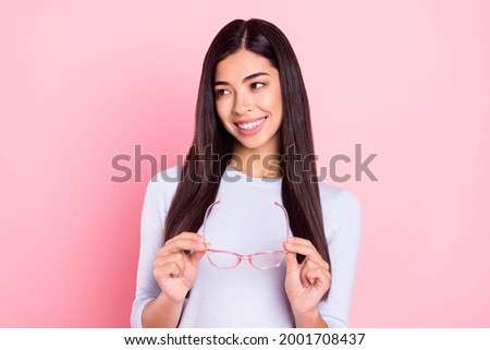 Portrait of attractive cheerful intellectual girl holding in hands specs thinking copy space isolated over pink pastel color background