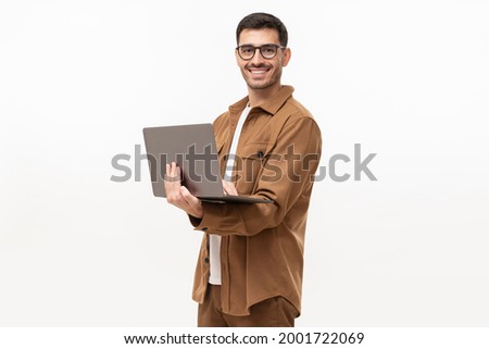 Young man standing holding laptop and looking at camera with happy smile, isolated on gray background