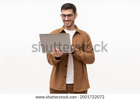 Young man holding laptop surfing, browsing online, typing message or watching movie isolated on gray background