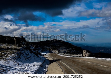 Mountain road of Serra da Estrela with snow and ice. Cloudy sky in the background