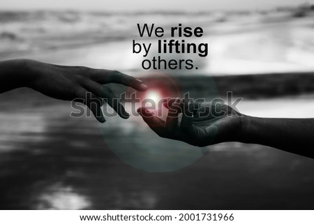 Inspirational quote - We rise by lifting others. With helping hands touch the light, reaching out each other. Strength kindness and humanity support concept in black white abstract art background Royalty-Free Stock Photo #2001731966