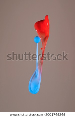 The blue water drops from above barely miss the red shot with pressure from below - Liquid Drop Art