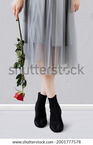 Woman standing in tiptoes holding a red rose