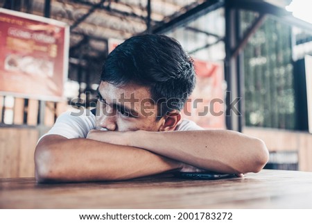 A depressed and lonely teen lying on the table at a outdoor food court. Low self esteem from facial acne. Royalty-Free Stock Photo #2001783272