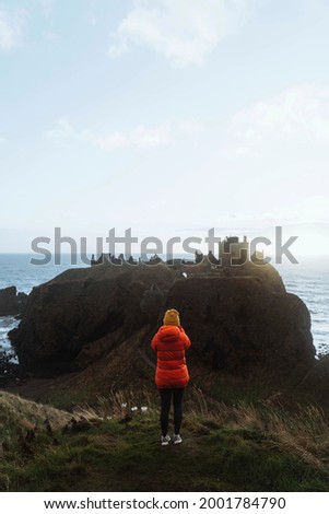 Female photographer taking photo of Dunnottar Castle, Scotland
