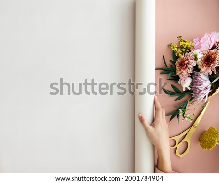 Florist rolling out a white banner on a pink desk