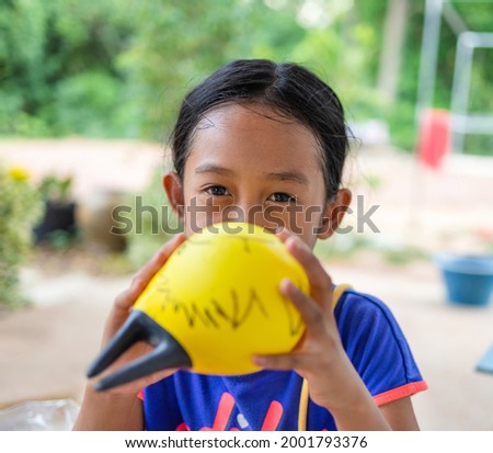 cute little asian girl blowing yellow balloons