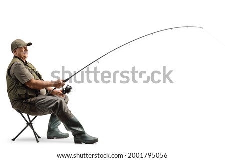 Profile shot of a mature fisherman sitting on a chair with a fishing rod isolated on white background Royalty-Free Stock Photo #2001795056