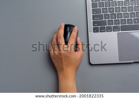 woman works with a laptop at home and holds a computer mouse in her left hand. Royalty-Free Stock Photo #2001822335