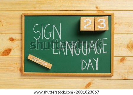 world sign language day written on green board yellow wooden background