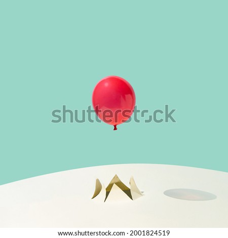 Red summer party balloon flying out of a crack on yellow and blue background. Minimal abstract concept. Square layout with copy space.