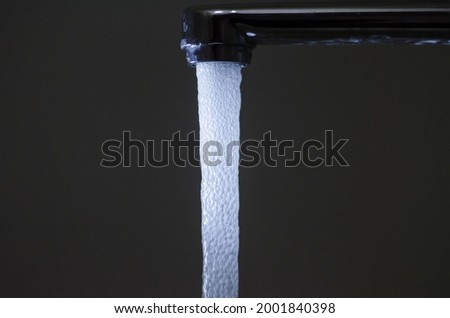Water with bubbles flows down from the water tap