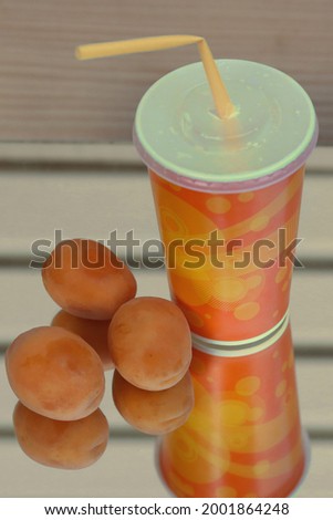 Apricot cocktails in a glass and apricots on a mirrored background.