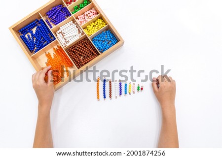Top view of girls hand is playing and sorting a puzzle of colored plastic beads in montessori school. Concept of using a mathematical geometry learning resources for children education.