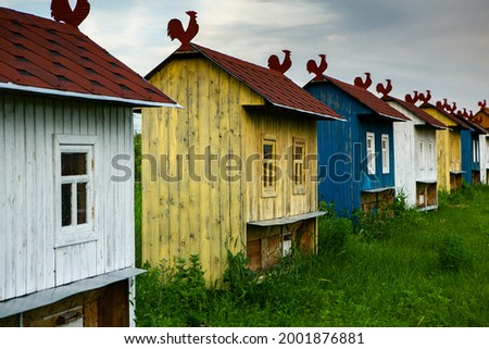 Colored bee houses on green meadow in countryside. Honey bee hives. Beautiful small decorative houses.