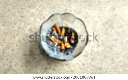 defocus picture of cigarette butts and cigarette ashes in a glass ashtray. a lot free space for your text.