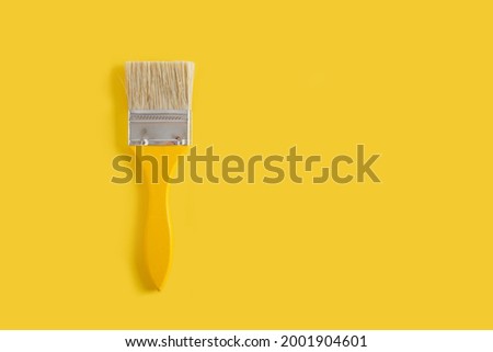 wooden yellow paint brushes on a yellow background copy space top view