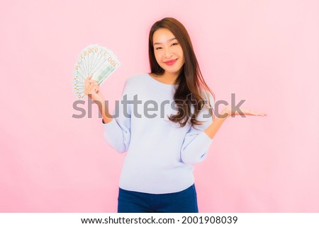 Portrait beautiful young asian woman with a lot of cash and money on pink color background