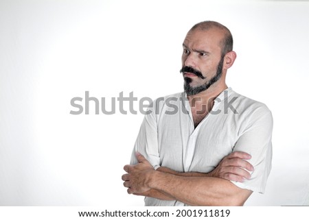 Caucasian man with mustache and beard making dubious and analytical expression, dressed in white on white isolated background