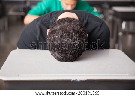 Portrait of a young high school student bored and frustrated with his head down on his desk Royalty-Free Stock Photo #200191565