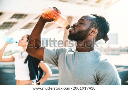 Fitness african athlete drinking energy drink outdoor - Fit people resting taking a break after workout - Healthy lifestyle concept