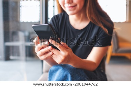 Closeup image of a beautiful young asian woman holding and using mobile phone