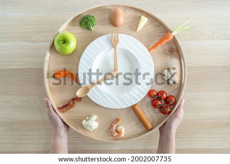 Intermittent fasting IF and keto diet concept with clock hours timer for eating nutritional or ketogenic food low carb, high fat and protien food meal healthy dish and skipping meal for weight loss Royalty-Free Stock Photo #2002007735