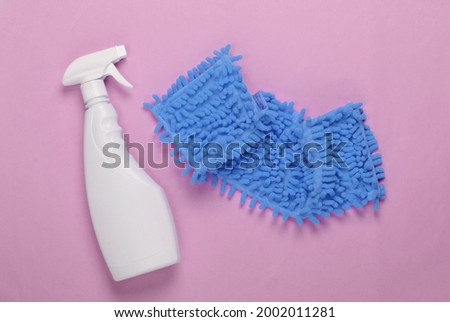 Rag for cleaning, spray bottle on pink background. Top view