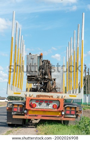 An empty truck is standing on the side of the road waiting for the cargo to be loaded. On the road, an empty logging truck with a manipulator on a sunny summer day. logging truck close-up.