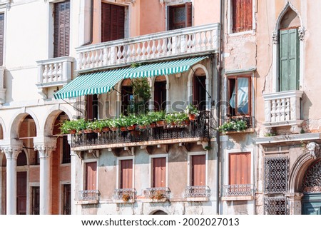 Large balcony with many flower pots on it. The facade of one of the old houses in Venice on the Grand Canal. Venice, Italy