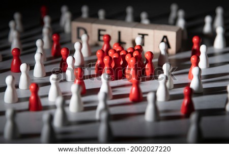 wooden blocks with the word delta surrounded by white and red wooden figurines. symbol for corona mutant delta. Royalty-Free Stock Photo #2002027220