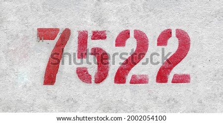 Red Number 7522 on the white wall. Spray paint. Number seven thousand five hundred twenty two.