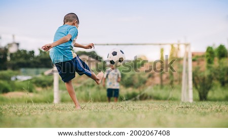 Action sport scene of a group of kids having fun playing soccer football for exercise in community rural area under the twilight sunset. Picture with copy space.