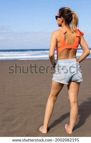 Caucasian girl, in bikini, observing at the sea