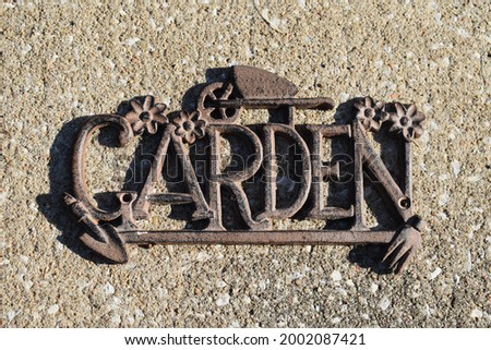 Metal garden sign with a concrete background