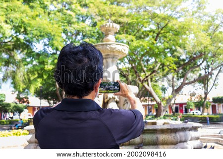 tourist taking a picture of fountain in central park of antigua guatemala