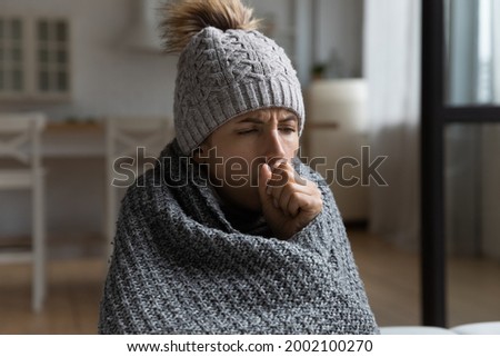 Unhealthy millennial hispanic woman wearing warm hat covered in knitted plaid coughing, suffering from first flue grippe covid 19 bronchitis respiratory disease, vaccination, healthcare concept.