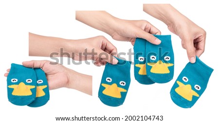 Collection of hand holding child socks isolated on white background. 