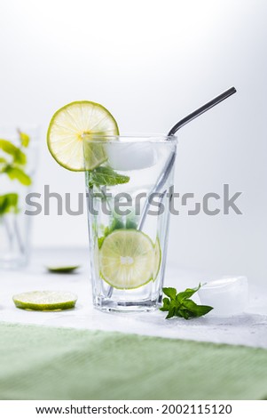 Mojito cocktail with lime and mint with straw on a white background