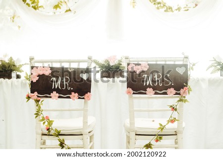 photograph with two chairs full of ornaments and flowers with a letter that says Mr and Mrs. concept weddings and marriage freedom and love. copy space background.