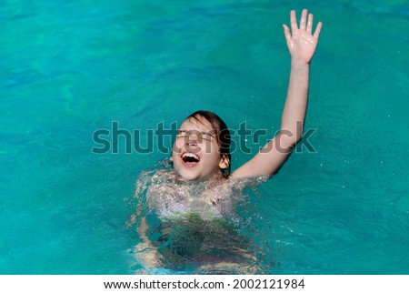 The girl drowns in water and raises her hand up calling for help. The girl drowns and screams.