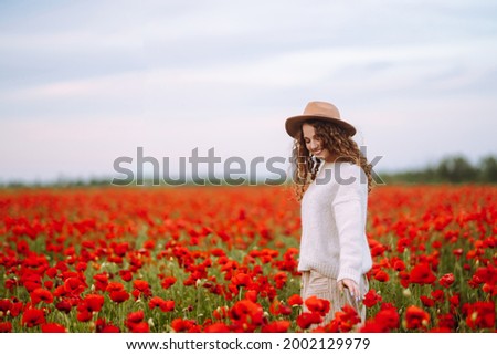Beautiful woman in a blooming poppy field. People, lifestyle, travel, nature and vacations concept.
